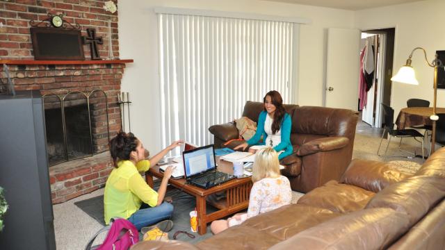 Three smiling students gather in renovated FPU student house to study