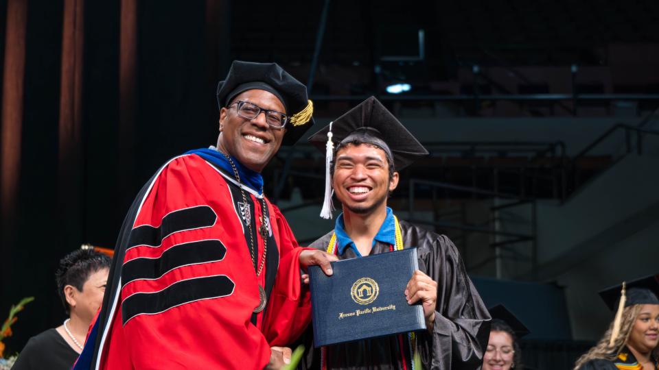 FPU President André Stephens, Ph.D., presents a diploma to a graduate during commencement ceremonies May 10.
