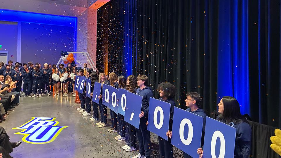 Students holds signs announcing $60 million dollar gift
