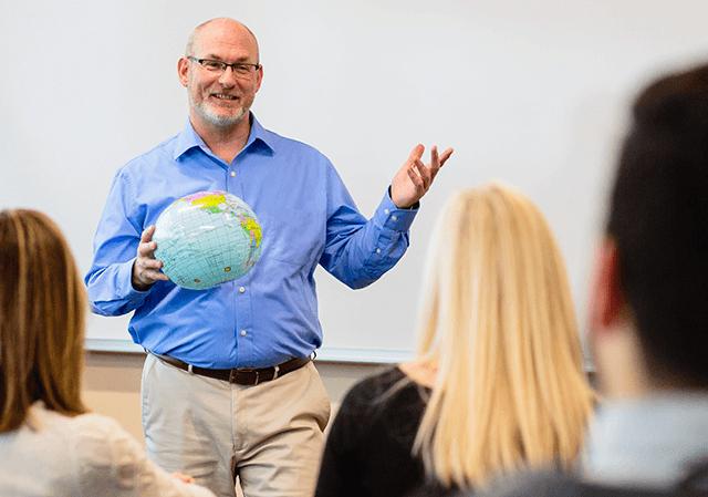 Mike Jones teaches class while holding inflatable globe