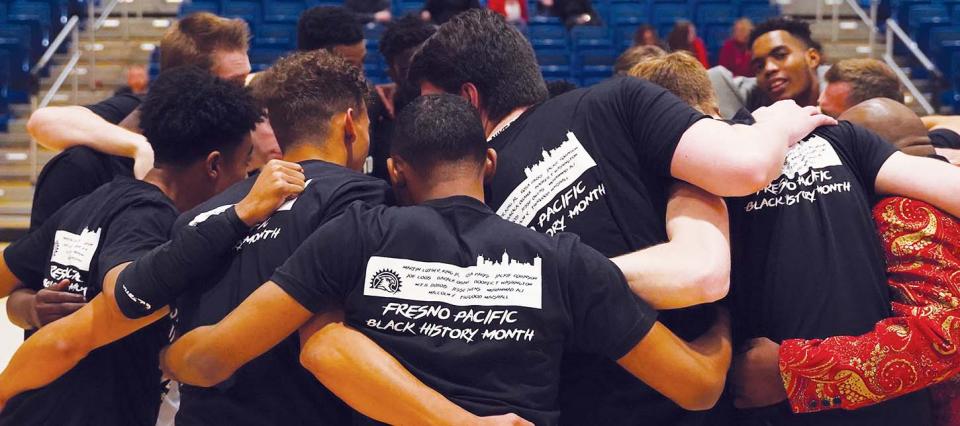 Basketball players huddled in circle with shirts that say Fresno Pacific Black History Month