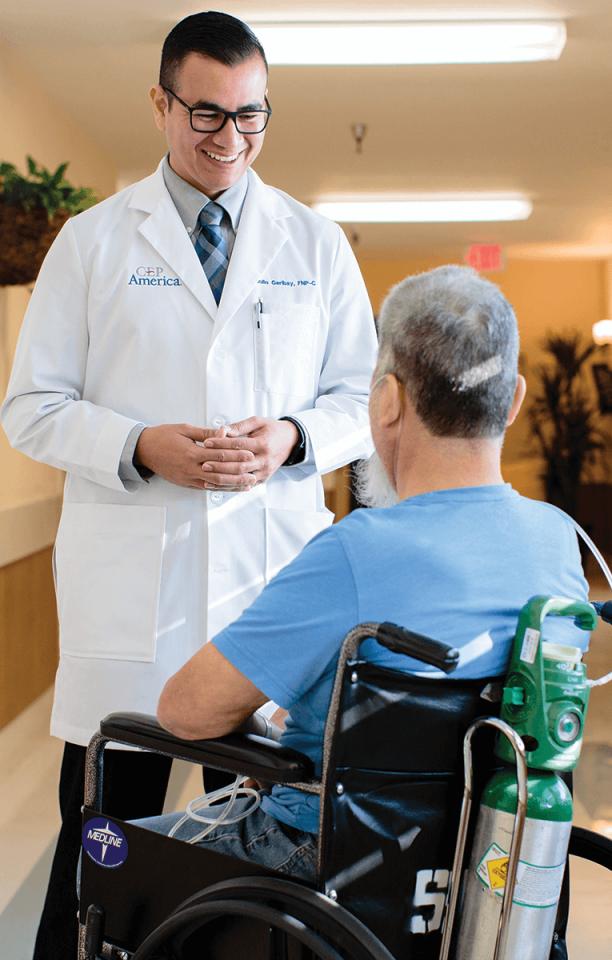 A smiling Julio Garibay addresses a wheelchair-bound patient