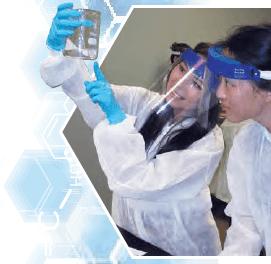 Two students wearing face shields and examining flask