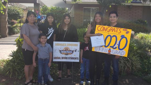 An FPU social work graduates celebrates with family and signs on their front lawn