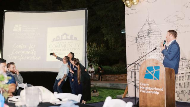 Members of the CCT staff take a selfie in front of the crowd while Andrew Feil smiles and looks on