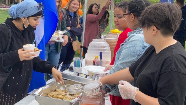 Students, faculty and staff selecting food served at tables outdoors