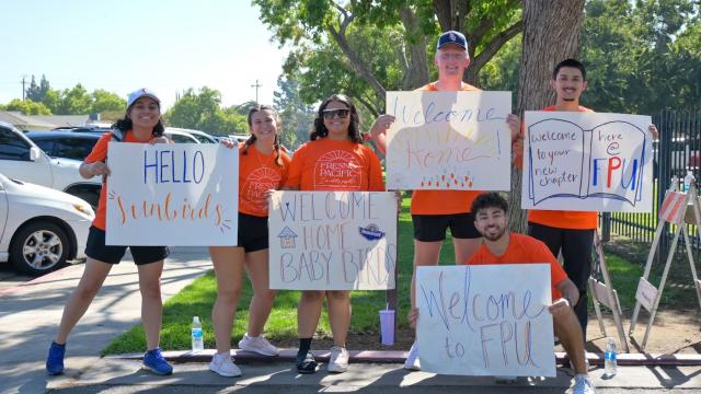 Returning students hold welcome signs for new students during FPU's New Student Orientation