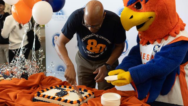 FPU President Andre Stephens cuts some cake for mascot Sunny the Sunbird during 80th Anniversary celebrations