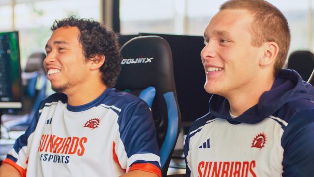Two esports team members wearing their jerseys while playing in the center