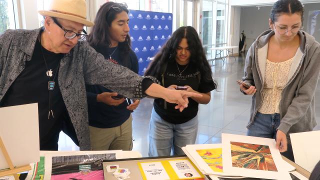 Carlos Perez David (left) talks to students about art in the lobby of the Warkentine Culture and Arts Center.