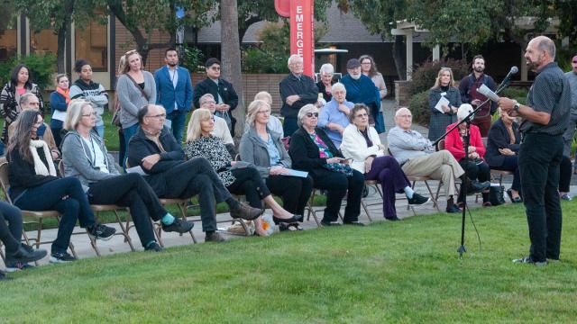 Tim Geddert speaks during the tree rededication. Debra and Laura, daughters of Henry and Elvera Schmidt, sit fourth and fifth, respectively from left in the front row.