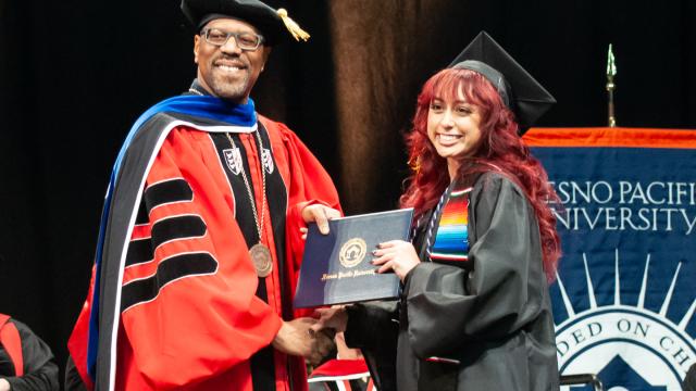 President Stephens hands a diploma to a new graduate