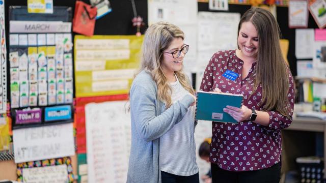 A student teacher and a master teacher compare notes in a classroom