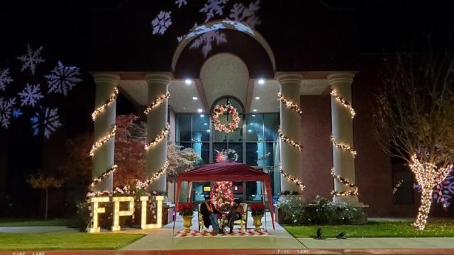 The front of McDonald Hall on the main campus lit for Christmas with President Joseph Jones and First Lady Yvette Jones sitting out front