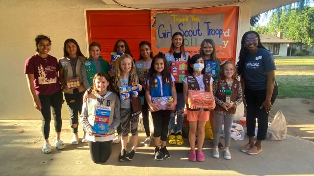 Photo of members of Girls Scout Troop 5011 in front of Sunbird Food Pantry, along with Taylor Starks