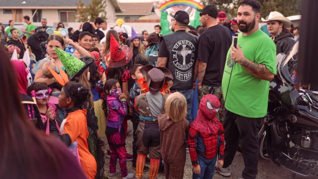Photo of Brandon Davison speaking to Halloween-costumed children and others at Classic Cars and Candy Bars