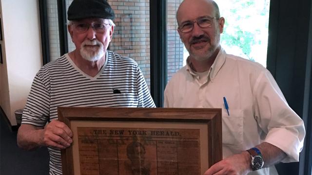 David Allen and Marshal Johnston, Ph.D., hold Allen's gift of an original framed newspaper page describing Lincoln's assassination