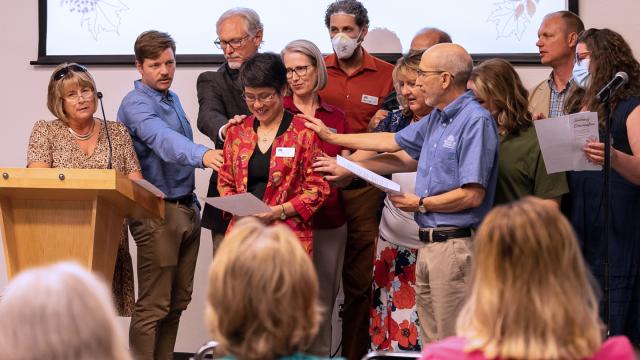 University administrators and seminary faculty and staff lay hands on Sharon Tan (center) to bless her time at Fresno Pacific Biblical Seminary.