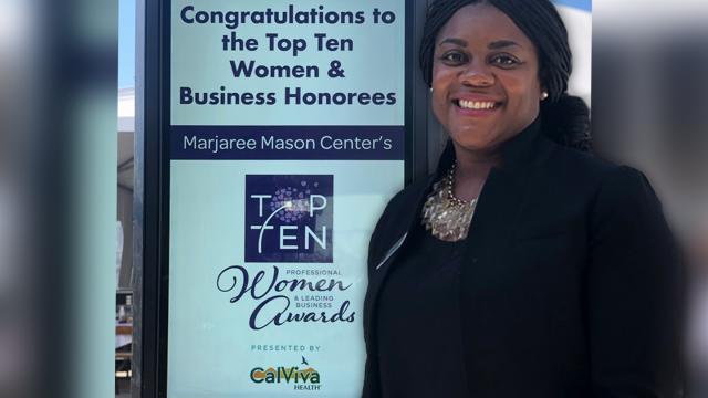 Shantay Davies-Balch standing next to the sign for the Marjaree Mason Center event