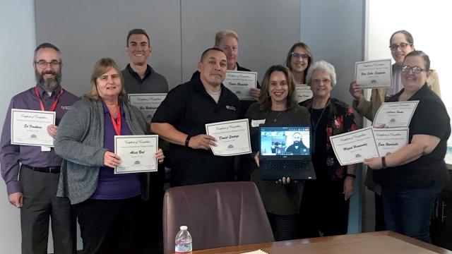 FPU faculty Michelle Bradford (front row, second from right, holding monitor) and Sharon Starcher (immediately behind and to the right of Bradford with Kern Health project managers at the training event.