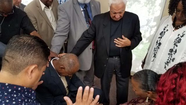 Guests at the President’s Prayer Breakfast pray over Joseph and Yvette Jones