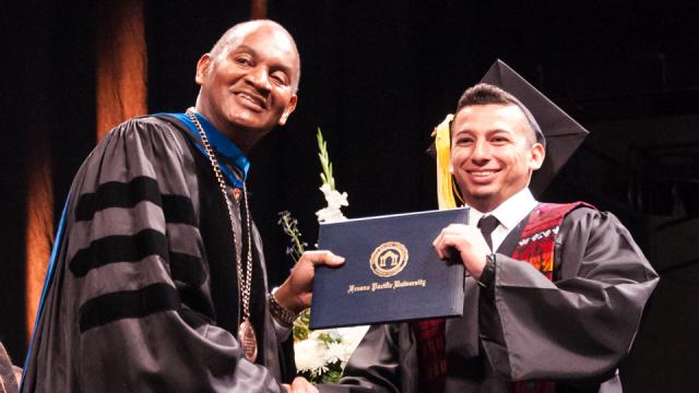 President Joseph Jones, Ph.D., poses with a new graduate