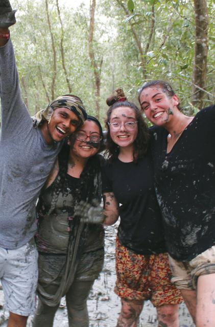 Four smiling students covered in mud