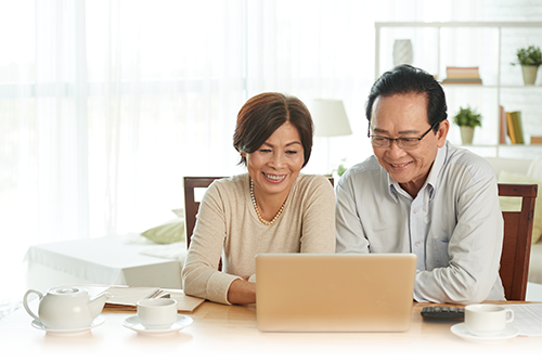 A middle aged couple laughing at a laptop