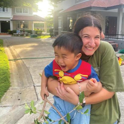 Photo of a college student hugging a child.