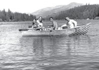Four people on a boat on a lake with mountains in the back